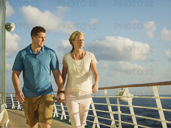 Caucasian couple holding hands on boat deck