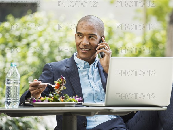 Black businessman working and eating lunch outdoors