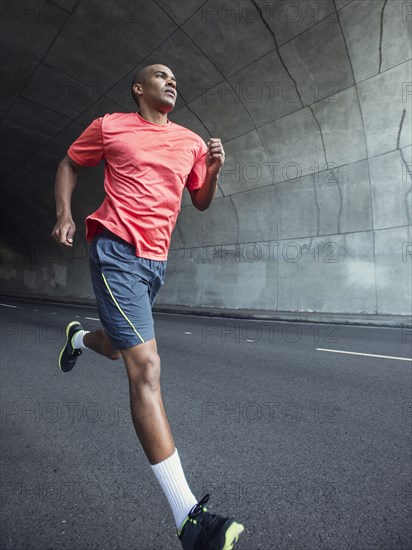 Black man running in urban tunnel
