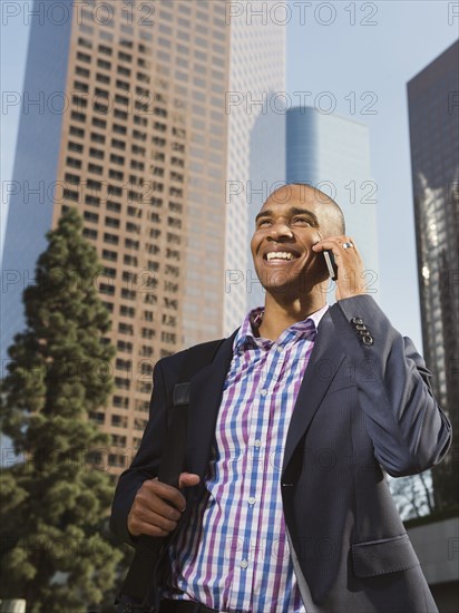 Black businessman talking on cell phone in city