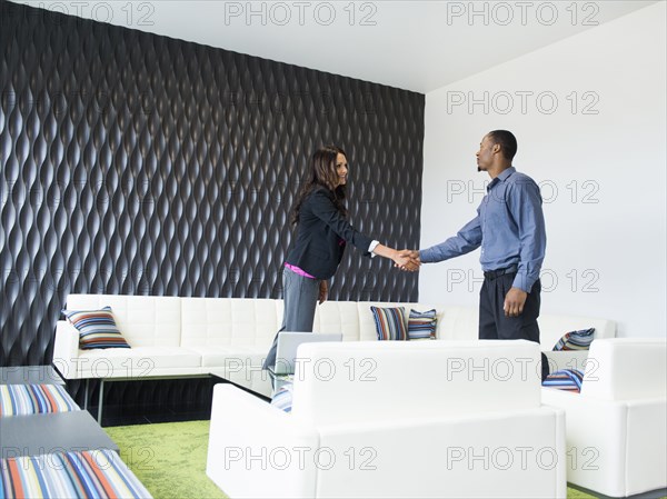 Business people shaking hands in office lobby