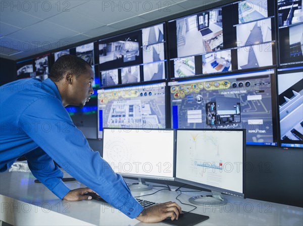 Black security officer watching surveillance cameras