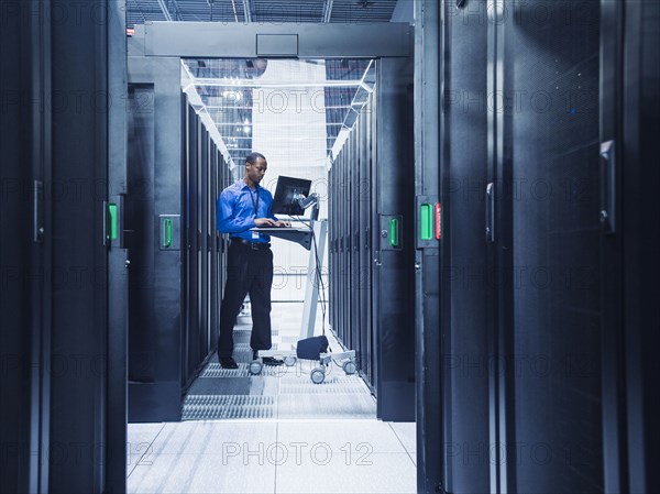 Black businessman using computer in server room