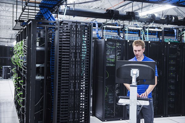 Caucasian technician using computer in server room