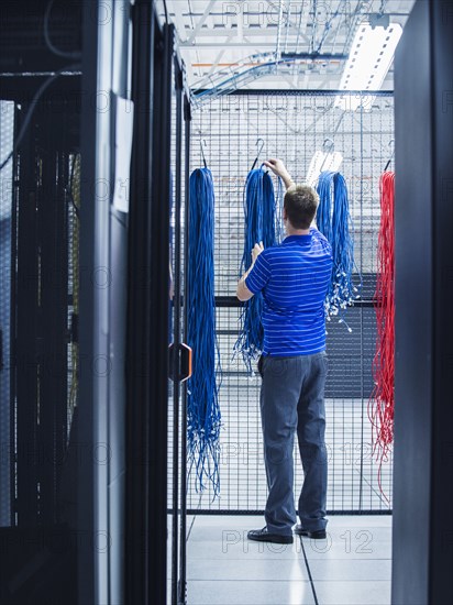 Caucasian technician hanging cables in server room