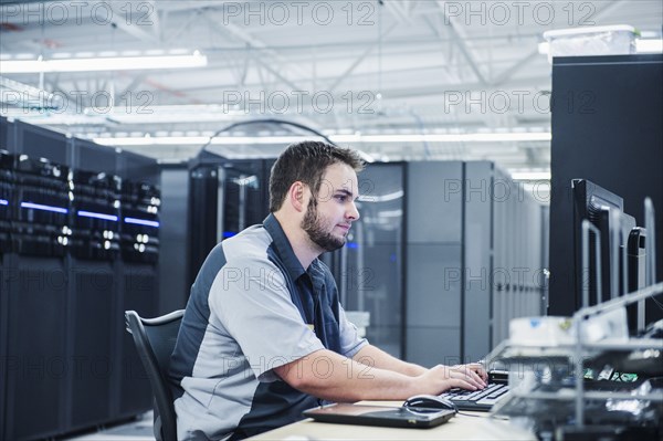 Caucasian technician using computer in server room