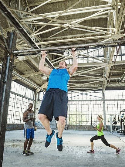 Athlete doing pull-ups in warehouse gym