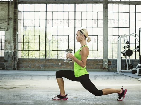 Caucasian woman lifting weights in warehouse gym