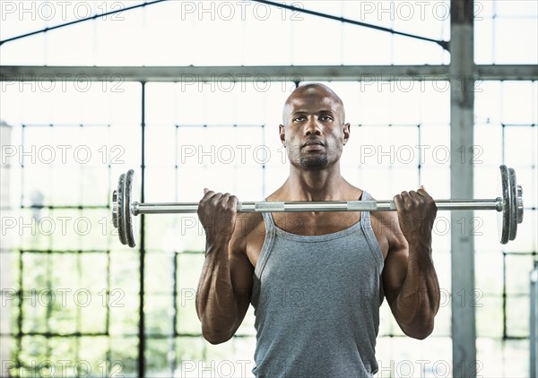 Black man lifting weights in warehouse