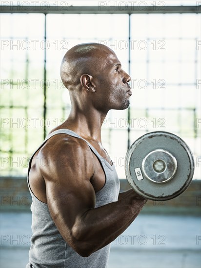 Black man lifting weights in warehouse