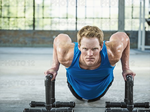 Caucasian man doing push ups in warehouse gym