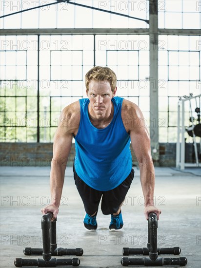 Caucasian man doing push ups in warehouse gym