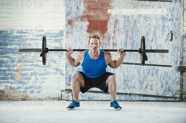 Caucasian man lifting weights in warehouse