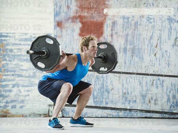 Caucasian man lifting weights in warehouse