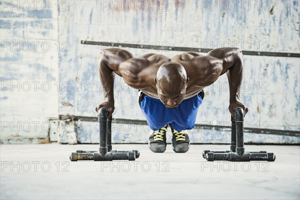 Black man doing push ups in warehouse