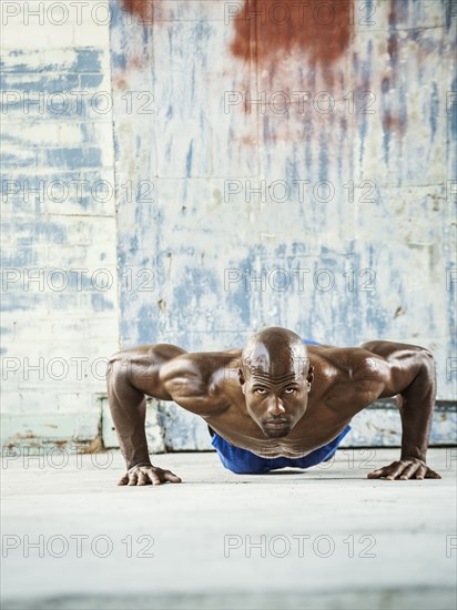 Black man doing push ups in warehouse