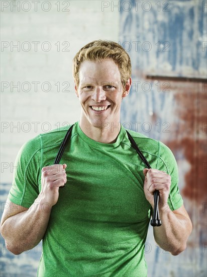 Caucasian man holding jump rope in warehouse
