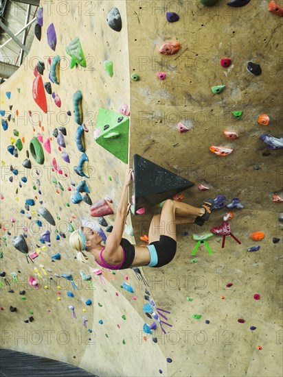 Caucasian woman climbing indoor rock wall