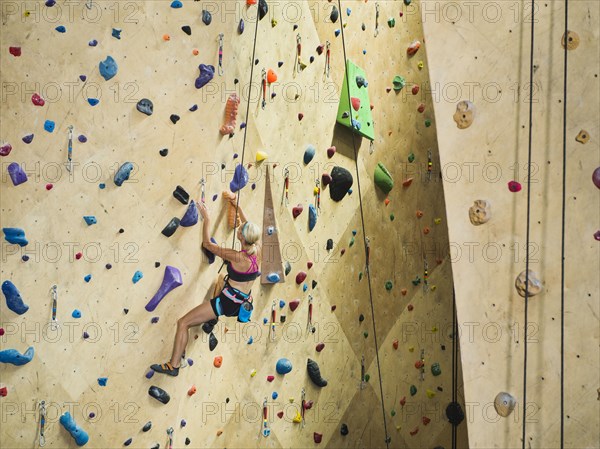 Caucasian woman climbing indoor rock wall