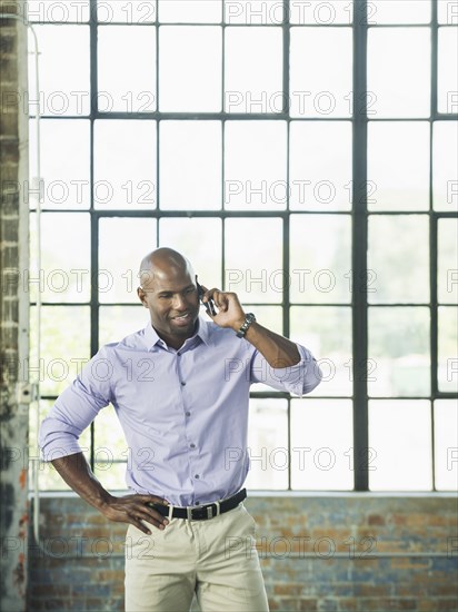 Black businessman talking on cell phone in warehouse