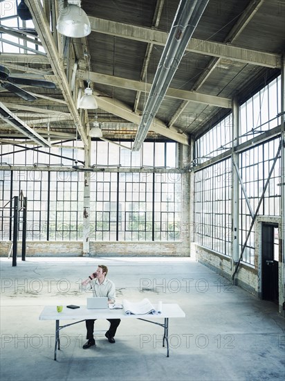 Caucasian businessman talking on cell phone in empty warehouse