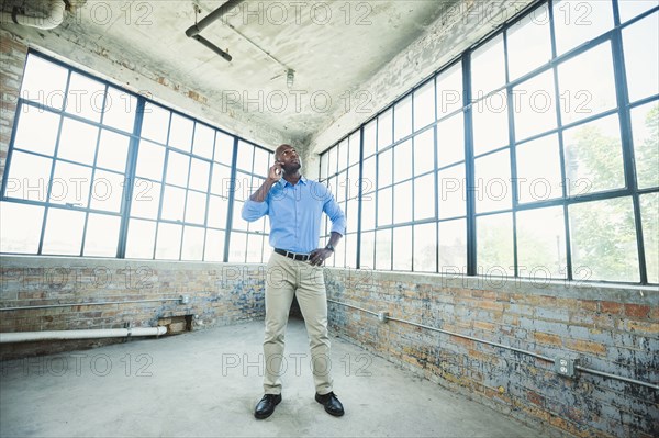 Black businessman talking on cell phone in warehouse