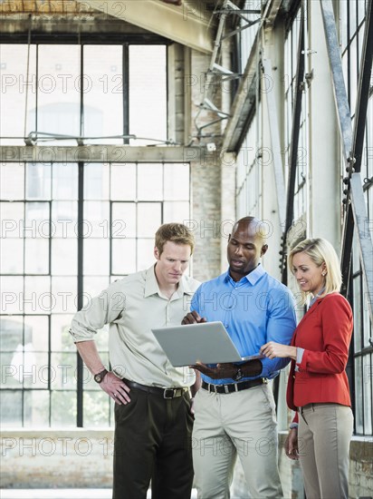 Business people using laptop in warehouse