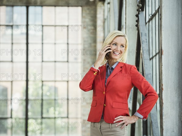 Caucasian businesswoman talking on cell phone in warehouse