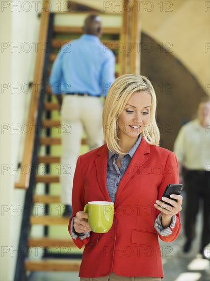 Businesswoman using cell phone near staircase