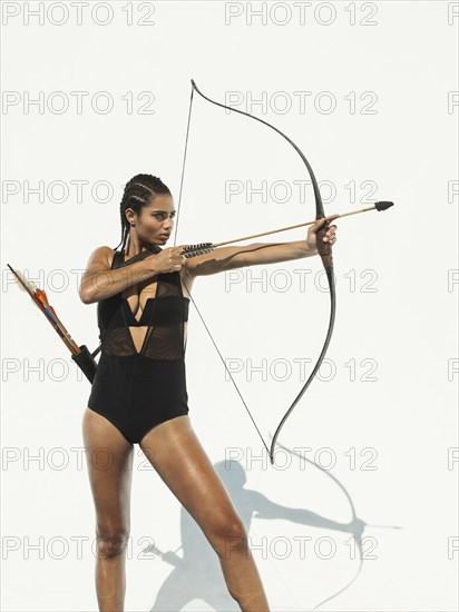 Mixed race woman aiming bow and arrow