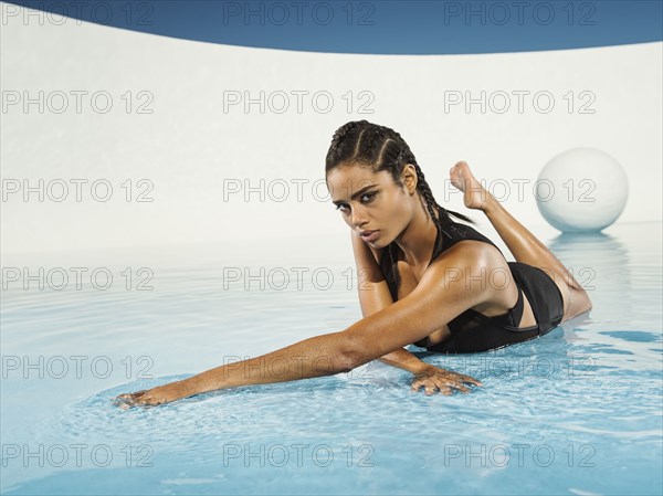 Mixed race woman laying on swimming pool surface