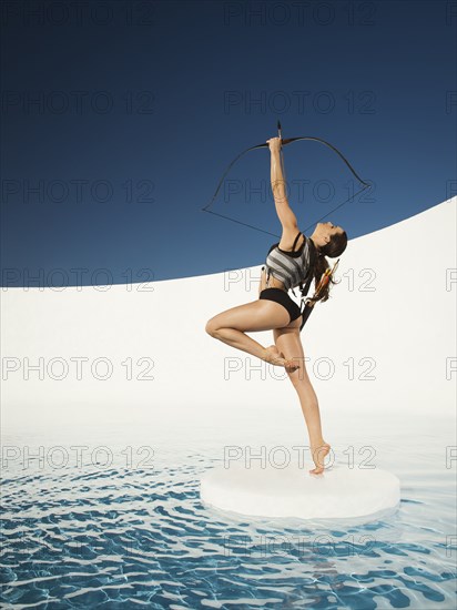 Caucasian woman aiming bow and arrow on ice floe