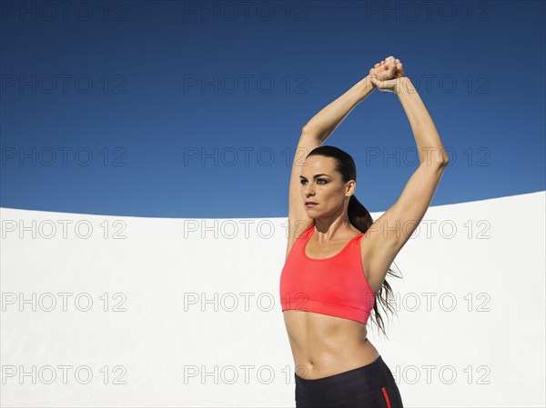 Caucasian woman stretching under blue sky