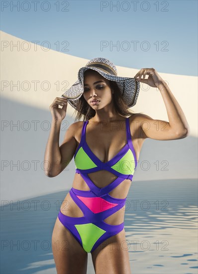 Mixed race woman wearing sun hat and colorful swimsuit