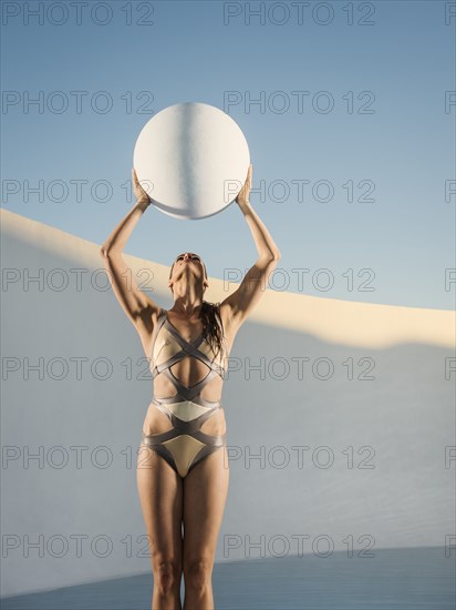 Caucasian woman holding sphere in swimming pool