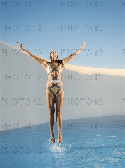 Caucasian woman jumping on swimming pool