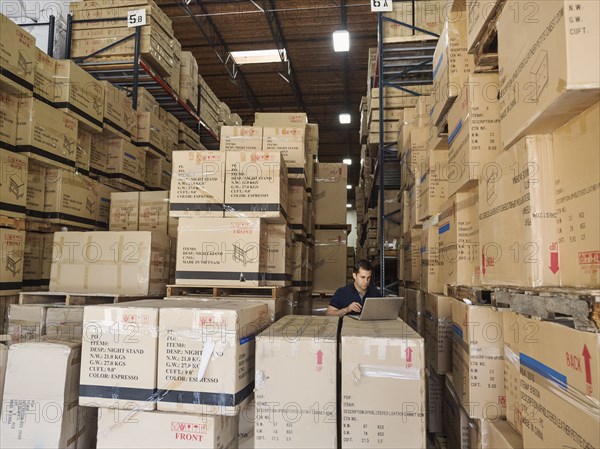 Caucasian worker using laptop in warehouse