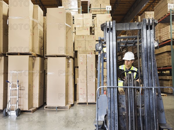 Caucasian worker driving forklift in warehouse