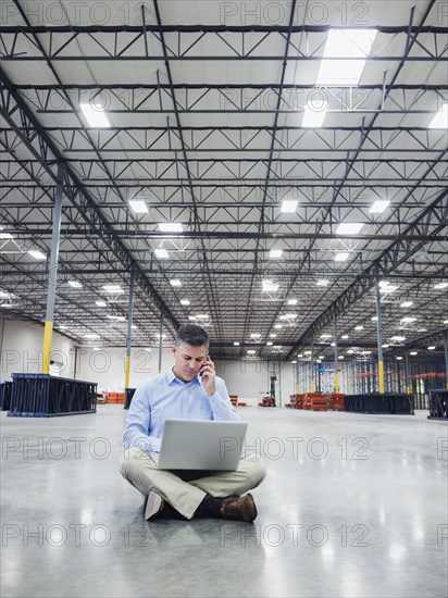 Caucasian businessman using laptop in empty warehouse