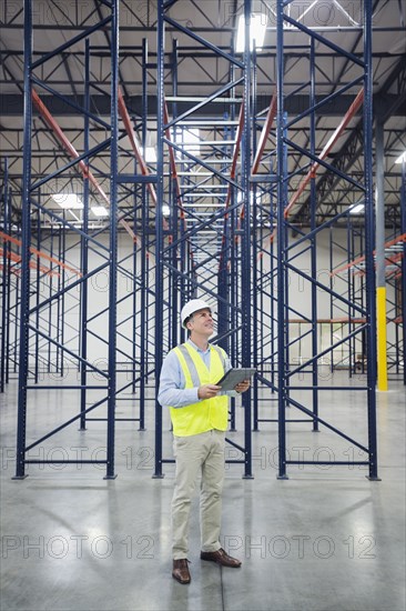 Caucasian worker using digital tablet in empty warehouse