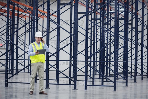 Caucasian worker using digital tablet in empty warehouse