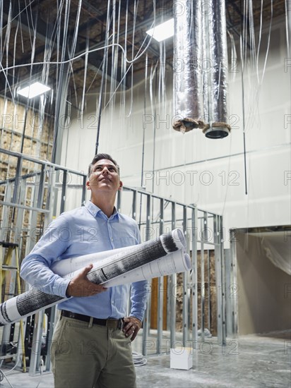 Caucasian architect carrying blueprints at construction site