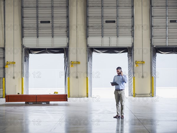 Caucasian businessman talking on cell phone in warehouse