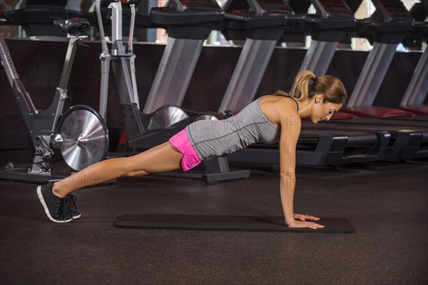 Caucasian woman doing push-ups in gym