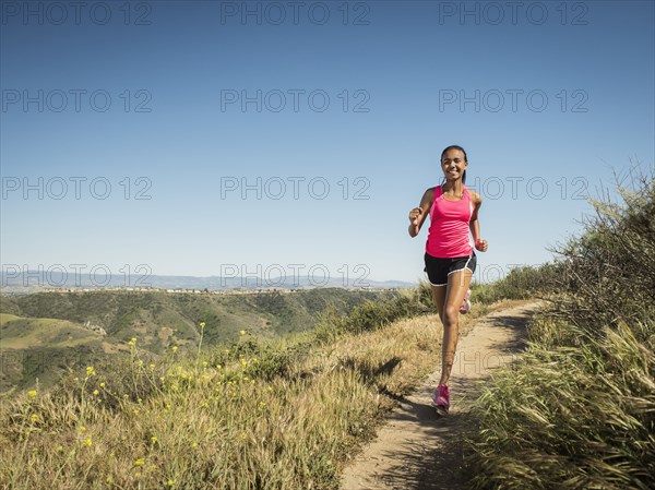 Mixed race girl running on hillside path