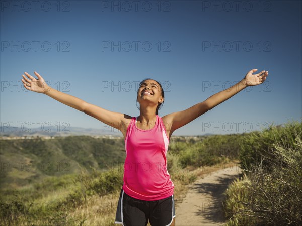 Mixed race girl cheering on hillside path