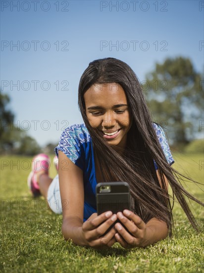 Mixed race girl using cell phone in park