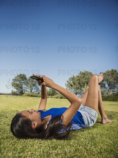 Mixed race girl using cell phone in park
