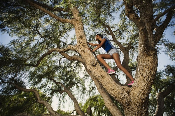 Low angle view of mixed race girl climbing tree