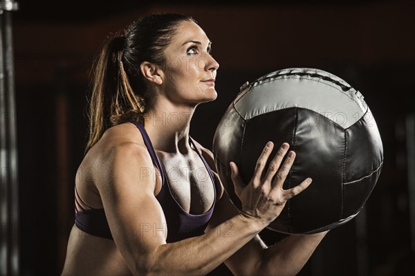 Caucasian athlete lifting resistance ball in gym